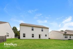 Fishers house for rent - A white house with a black door and windows is in the foreground of a grassy field.