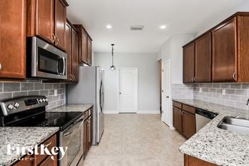 Ruskin house for rent - A kitchen with brown cabinets and a white door in the background.
