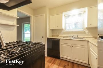 Garland house for rent - A kitchen with a black stove top oven and white cabinets.