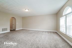 Blacklick house for rent - A spacious room with a carpeted floor and a door on the left side.