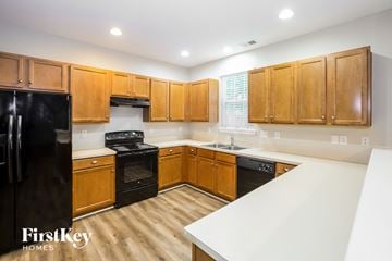 Charlotte house for rent - A kitchen with wooden cabinets and black appliances.
