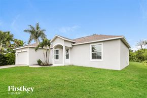 Englewood house for rent - a white house with a green lawn and a palm tree