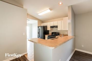 Riverview house for rent - a kitchen with white cabinets and a counter top and a black refrigerator