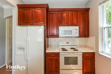 Homestead house for rent - a kitchen with wooden cabinets and white appliances and a refrigerator