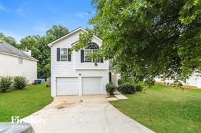 Mcdonough house for rent - A white house with a garage is surrounded by greenery.