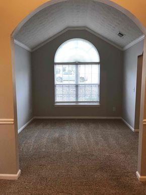 Mcdonough house for rent - A room with a large arched window and carpeted floor.