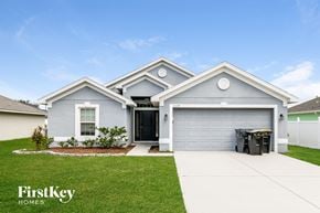 Poinciana house for rent - a white and blue house with a driveway and grass