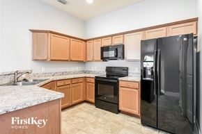 Poinciana house for rent - a kitchen with black appliances and wooden cabinets