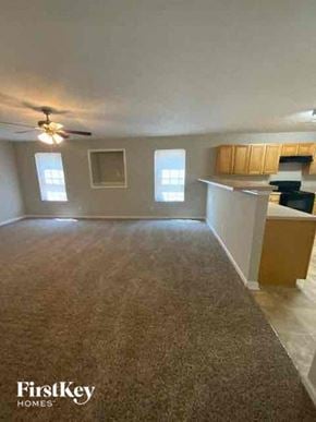 Covington house for rent - an empty living room and kitchen with a ceiling fan