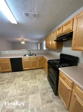 Covington house for rent - a kitchen with wooden cabinets and a black stove