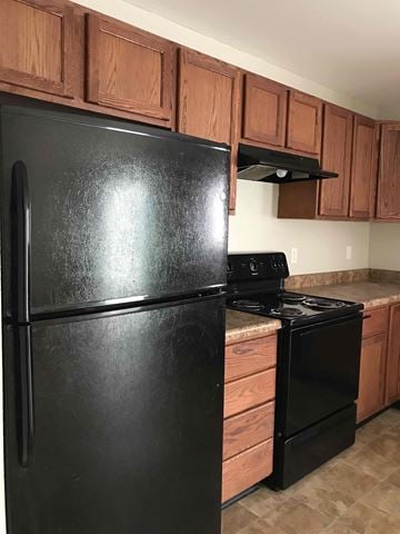 Indianapolis house for rent - A black refrigerator and stove in a kitchen with brown cabinets.