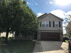 Indianapolis house for rent - A house with a brown garage door and a tree in front.