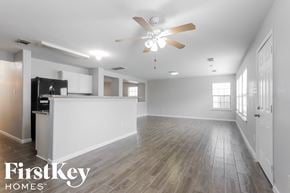 Tomball house for rent - A spacious, empty room with a ceiling fan and wooden flooring.