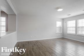 Tomball house for rent - A spacious room with wooden flooring and windows on the wall.