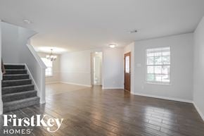 Tomball house for rent - A spacious room with wooden flooring and a staircase on the left side.