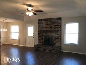 Crowley house for rent - an empty living room with a brick fireplace and a ceiling fan