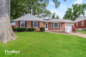 Saint Louis house for rent - a brick house with a green lawn and a tree