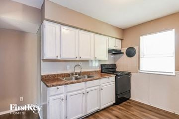 Saint Louis house for rent - a kitchen with white cabinets and a sink and a stove