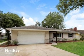 Deltona house for rent - A house with a garage and a tree in front of it.