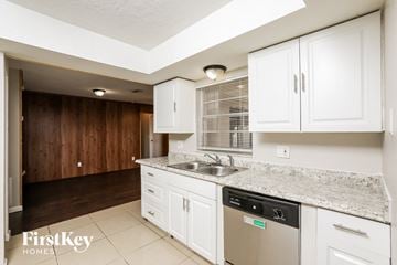 Deltona house for rent - A kitchen with white cabinets and a granite countertop.