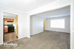 Indianapolis house for rent - A spacious room with a carpeted floor and a window with white curtains.