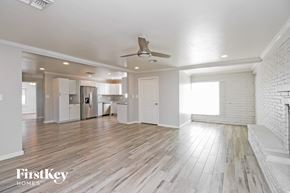 Tempe house for rent - an empty living room with a ceiling fan and a kitchen