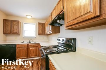Indianapolis house for rent - a kitchen with wood cabinets and black appliances and white countertops
