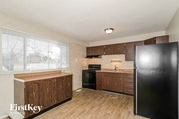 Florissant house for rent - A kitchen with wooden cabinets and a black refrigerator.