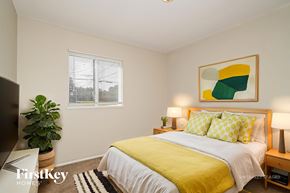 Florissant house for rent - A bedroom with a bed, a potted plant, and a painting on the wall.