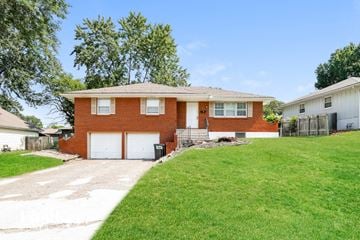 Raytown house for rent - a brick house with a white garage door and a lawn