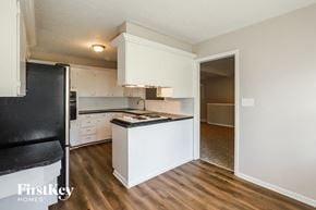 Raytown house for rent - an empty kitchen with white cabinets and a black refrigerator