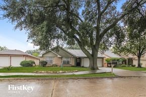 Houston house for rent - A wet residential street with a tree in the foreground and houses in the background.