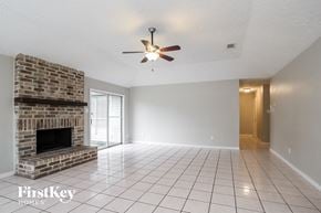 Houston house for rent - A spacious room with a brick fireplace and a ceiling fan.