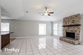 Houston house for rent - A spacious living room with a brick fireplace and a ceiling fan.