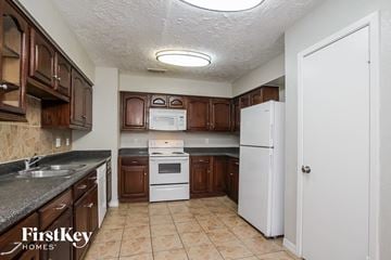 Houston house for rent - A kitchen with brown cabinets and a white refrigerator.