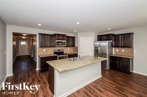 Vance house for rent - a kitchen with brown cabinets and a marble counter top