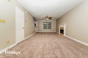 Jonesboro house for rent - an empty living room with carpet and a ceiling fan