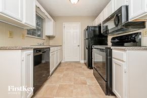 Jonesboro house for rent - a kitchen with white cabinets and a black stove and refrigerator