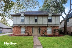 Houston house for rent - front view of a brick house with white siding and a sidewalk