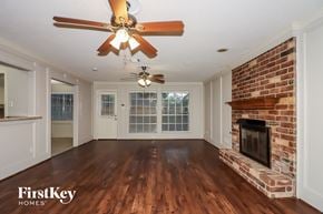 Houston house for rent - a living room with a brick fireplace and a ceiling fan