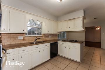 Houston house for rent - a kitchen with white cabinets and counters and a sink