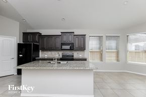 Haslet house for rent - a kitchen with black cabinets and a granite counter top