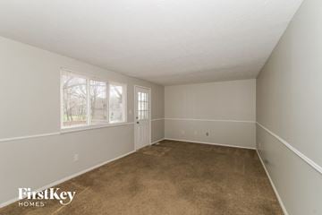 Indianapolis house for rent - A room with a carpeted floor and a window with trees visible outside.