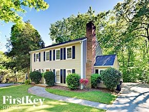 Charlotte house for rent - a yellow house with a brick chimney and a sidewalk in front of trees