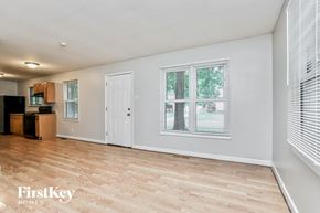 Florissant house for rent - A spacious room with wooden flooring and a large window.