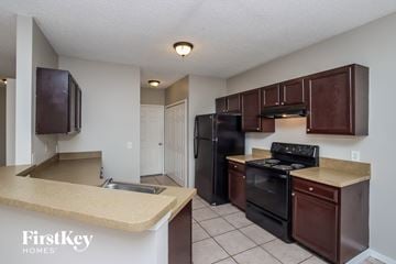Sebastian house for rent - A kitchen with brown cabinets and black appliances.