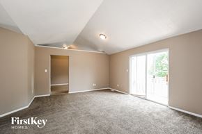 Florissant house for rent - the living room of an empty house with carpet and a door to the patio