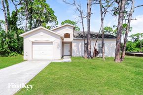 Sebastian house for rent - A white house with a garage is surrounded by trees.