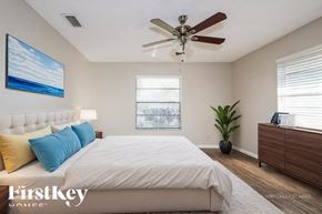 Wellington house for rent - A bedroom with a large bed, a ceiling fan, and a painting on the wall.