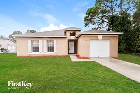 Sebastian house for rent - A beige house with a white garage door and a driveway leading to it.
